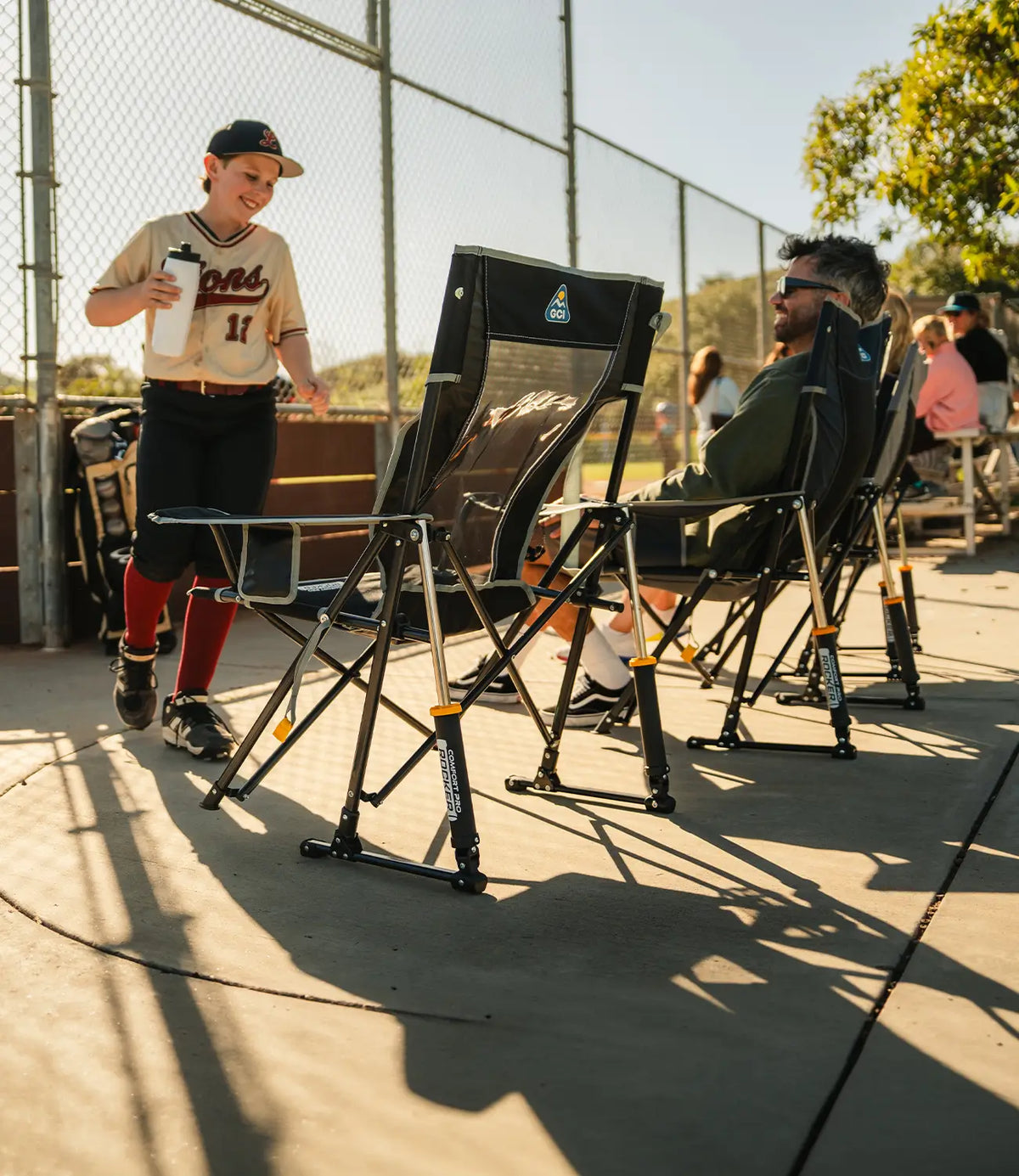 A parent smiling at their child who is playing baseball while they sit in a black Comfort Pro Rocker Chair.
